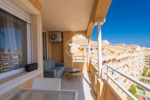 Un balcon avec un canapé, une petite table et une fenêtre équipée de stores.