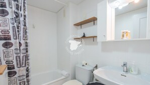 A bathroom with a white toilet, a sink, a mirror, and a shower curtain with a pattern.