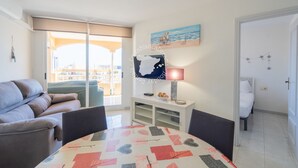 Een moderne woonkamer met een bank, een eettafel en een aan de muur bevestigde televisie.