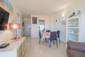 Un coin repas avec une table dressée pour quatre personnes, un canapé et un meuble contenant de la verrerie.
