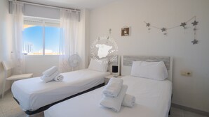 Een hotelkamer met twee bedden, een stoel, een bureau en een raam met gordijnen.