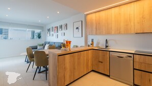 Une cuisine moderne avec des meubles en bois, un lave-vaisselle et un coin repas comprenant des chaises et une table.
