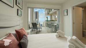 Une chambre d’hôtel moderne avec balcon, un coin repas et une vue sur les toits de la ville.