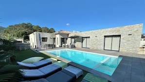 A modern outdoor pool area with lounge chairs and a stone building. - Villa Porto-Vecchio with swimming pool 8 persons (Lecci)