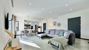 A modern living room with a sectional sofa, a dining area, and a kitchen in the background. - Villa Porto-Vecchio with swimming pool 8 persons (Lecci)