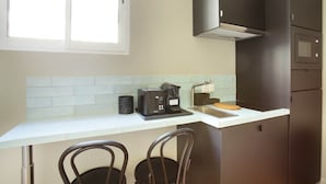 Una cucina compatta con una macchina del caffè, un forno a microonde e un tostapane sul piano di lavoro.