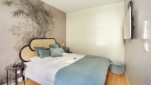 Camera da letto con un letto, un comodino, una TV a parete e un murale decorativo.