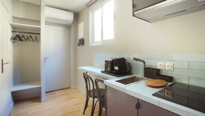 Una cucina compatta con piano cottura integrato, macchina da caffè e tagliere sul ripiano.