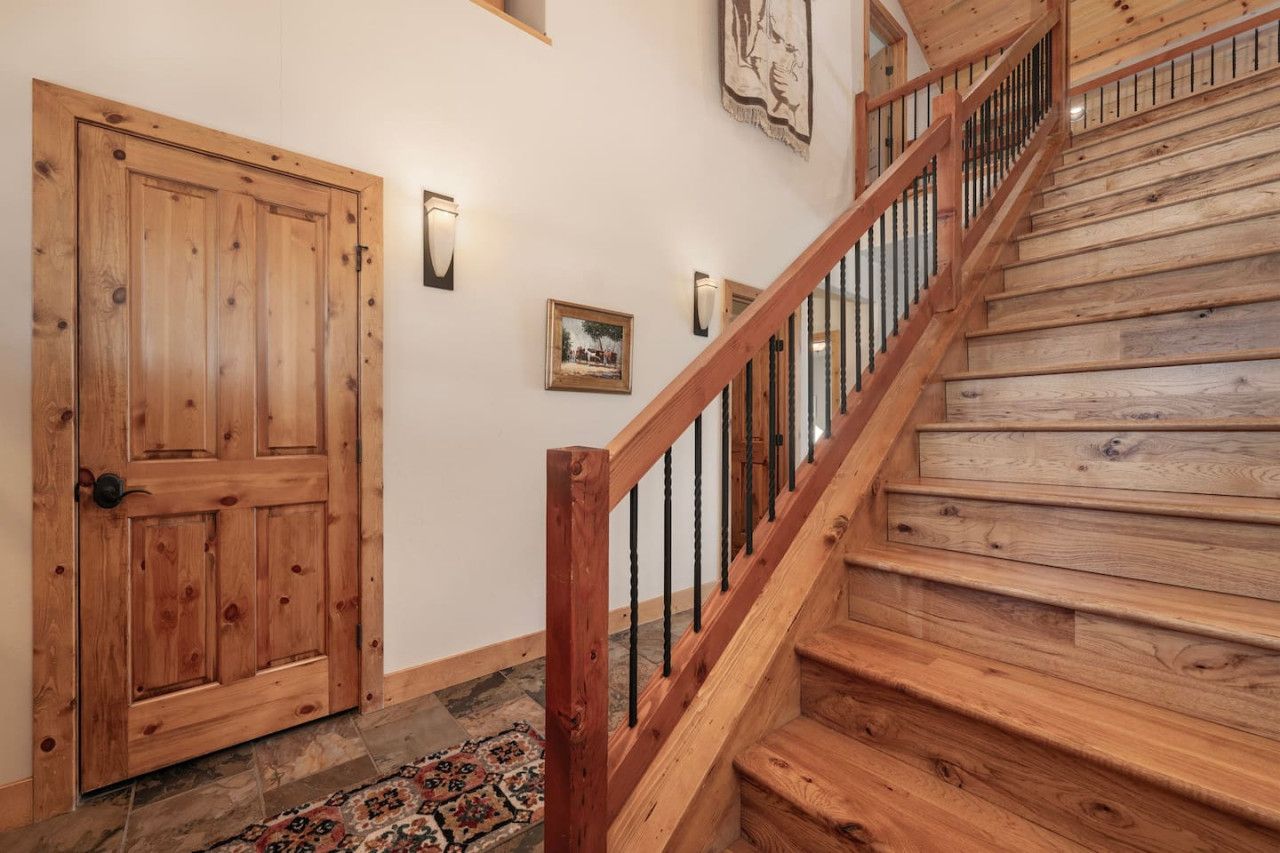 A wooden staircase with a handrail and a door with a black handle.