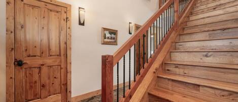 A wooden staircase with a handrail and a door with a black handle.
