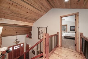 A wooden staircase leading to a bedroom with a bed and a framed picture on the wall.