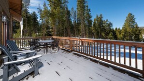 Eine Holzterrasse mit Sitzgelegenheit und Blick auf eine verschneite Landschaft.