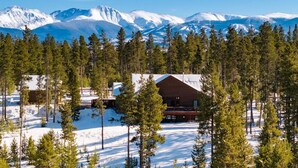 Eine Lodge, umgeben von schneebedeckten Bergen und dichten Kiefern.