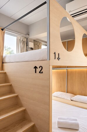 A modern interior with a wooden staircase, a bunk bed, and a small desk area.