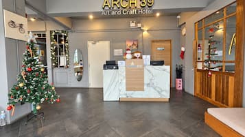 Uma área de recepção com árvore de Natal, balcão de recepção e uma placa com a inscrição 'ARCH 39 Art and Craft Hotel'.