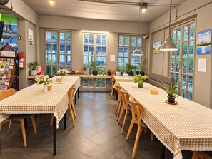 A dining area with checkered tablecloths, wooden chairs, and potted plants. - Mandalar Arch 39 Hotel (Chiang Mai)