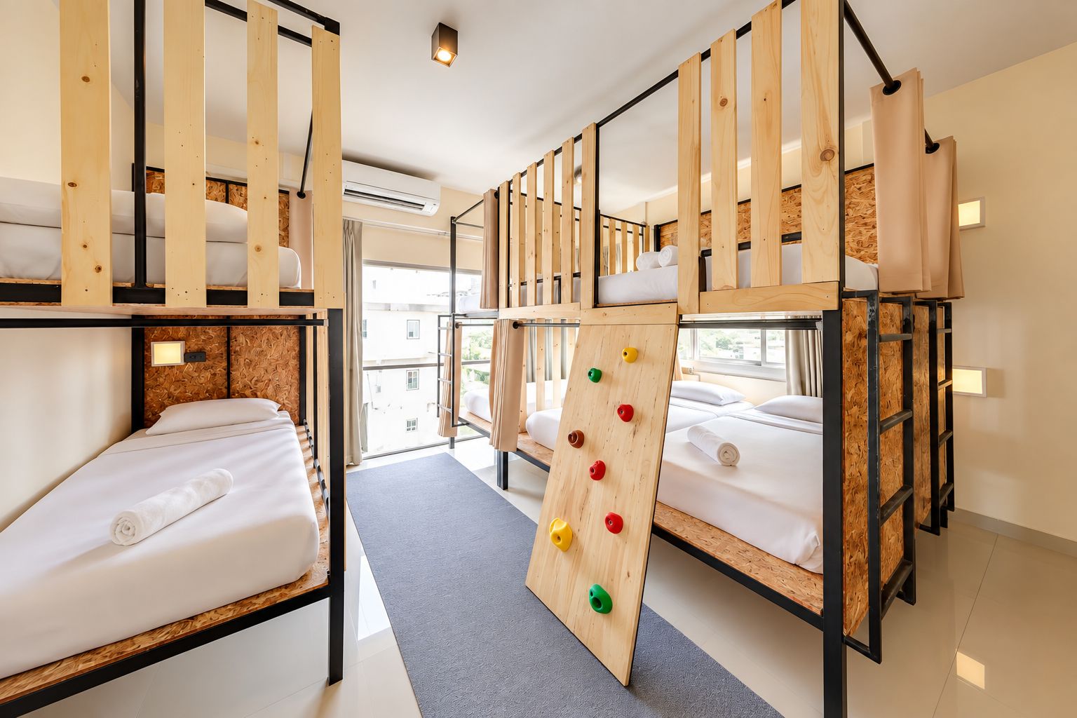 Une chambre avec des lits superposés, un mur d’escalade et une fenêtre donnant sur l’extérieur.