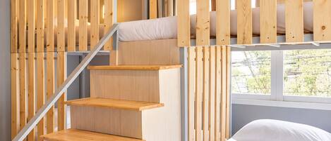 A room with a wooden staircase, a bed, and a window.