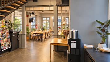 Interior moderno com escada, balcão de recepção e área de refeições com mesas e cadeiras.