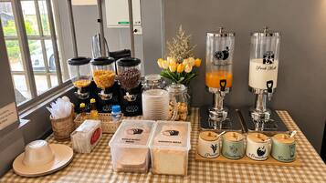 Buffet de café da manhã com diversos alimentos e máquinas de bebidas.