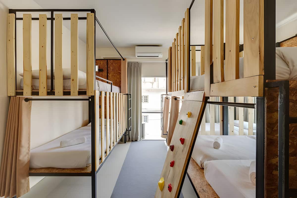 A hotel room with bunk beds, a wooden climbing wall, and a view of the city.