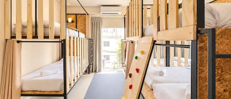 Quarto de hotel com beliches, uma parede de escalada e vista para a cidade.