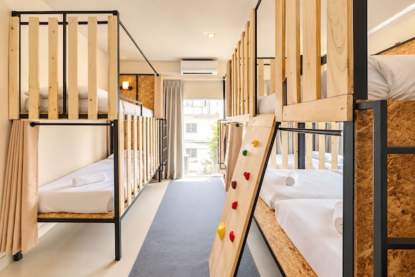 A hotel room with bunk beds, a climbing wall, and a view of the city. - Mandalar Arch 39 Hotel (Chiang Mai)