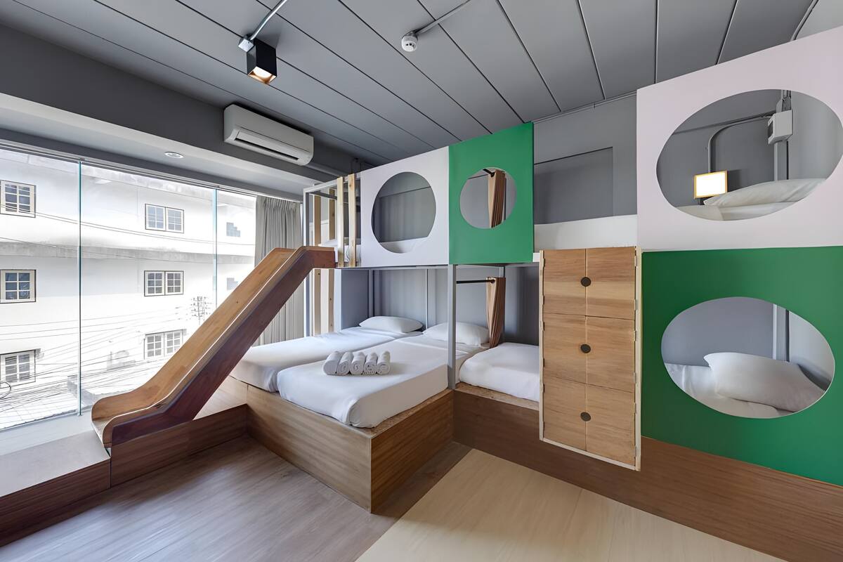 A modern hotel room with a wooden staircase, bunk beds, and circular mirrors.