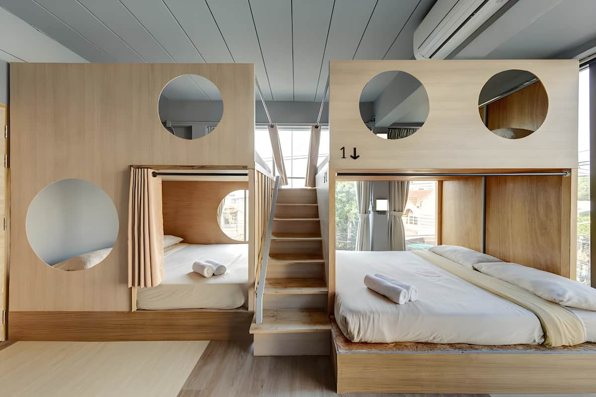 A modern hotel room with a wooden interior, a staircase, and a bed with a headboard.