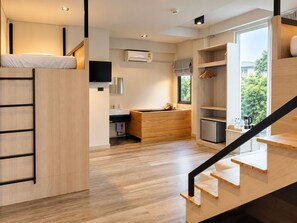 A modern, compact kitchen with a built-in stove, a sink, and a window providing a view of greenery outside. - Mandalar Arch 39 Hotel (Chiang Mai)