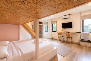 A bedroom with a loft-style bed, a desk with two chairs, a television, and an air conditioning unit.