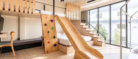 Un interior moderno con una pared de escalada de madera, un tobogán y vistas al exterior.