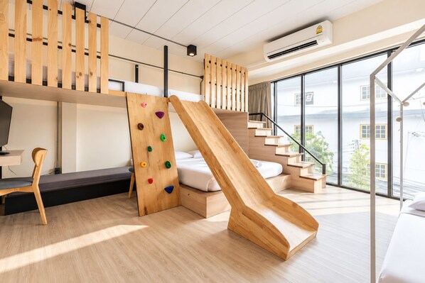 Un intérieur moderne avec un mur d’escalade en bois, un toboggan et une vue sur l’extérieur.