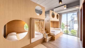 Quarto de hotel moderno com interior em madeira, escada e uma janela grande com vista para a cidade.