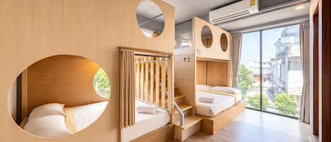 Habitación de hotel moderna con detalles de madera, una escalera y un ventanal que ofrece vistas a la ciudad.