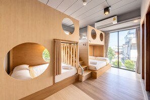 Habitación de hotel moderna con detalles de madera, una escalera y un ventanal que ofrece vistas a la ciudad.