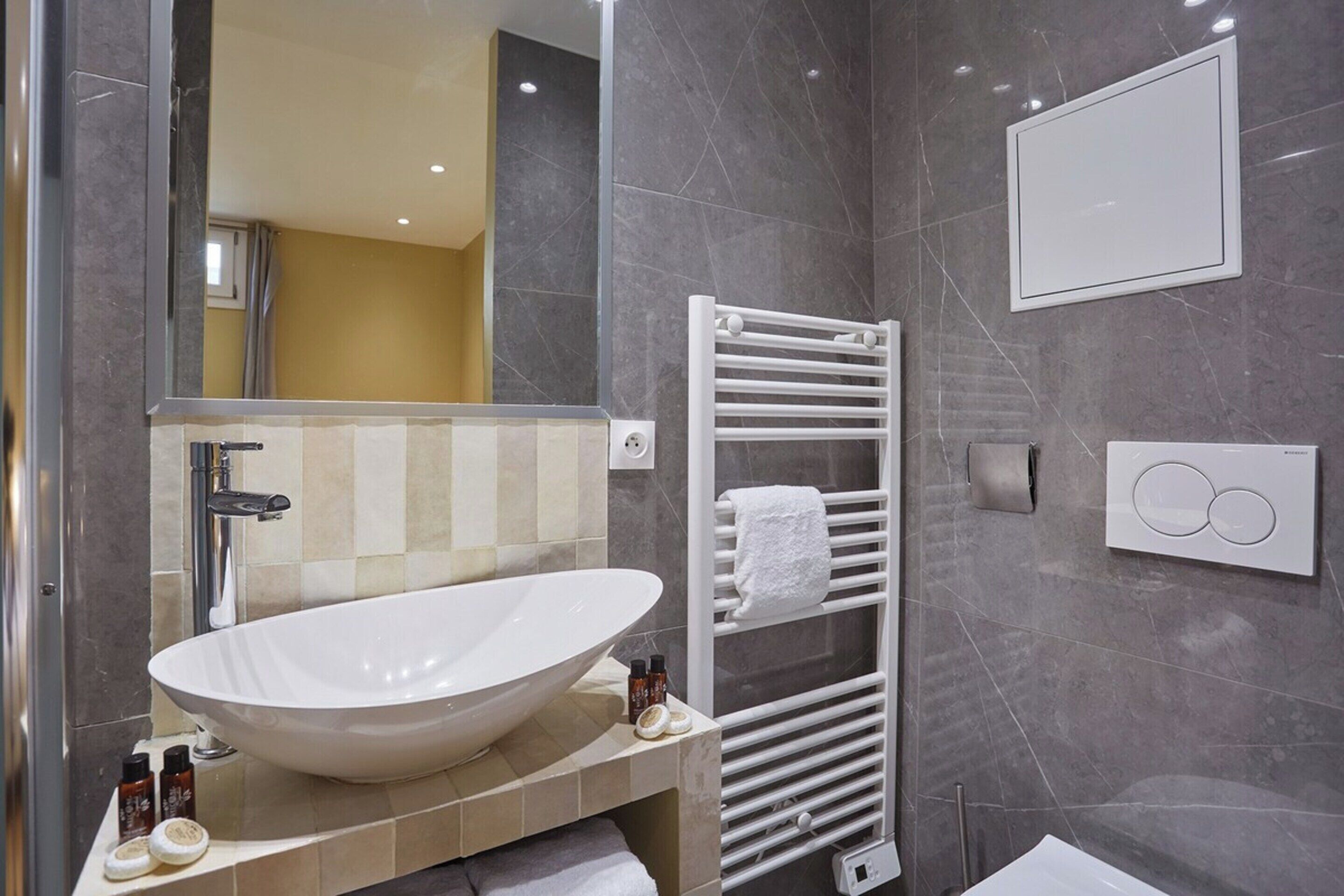 A modern bathroom with a large oval sink, a towel rack, and a mirror.
