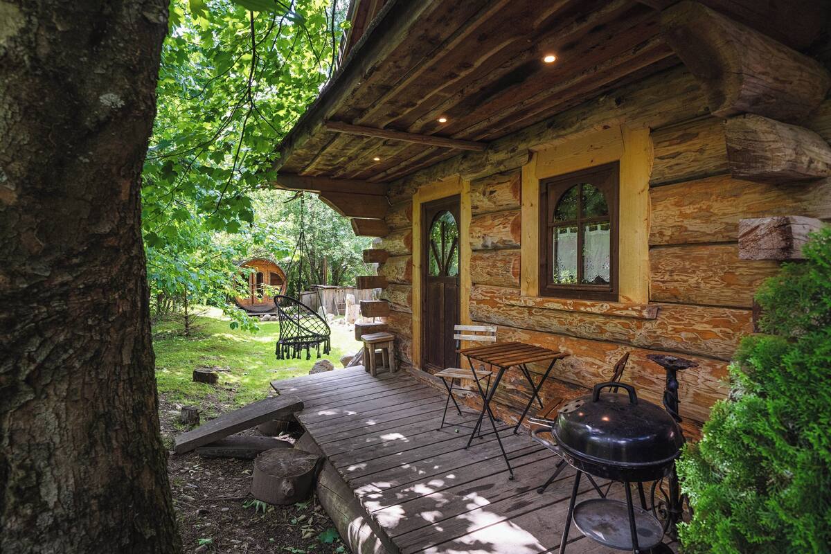 Een rustieke chalet met een houten terras, een barbecue en tuinmeubilair.