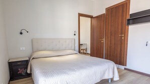 A bedroom with a bed, a nightstand, a wardrobe, and a mirror.