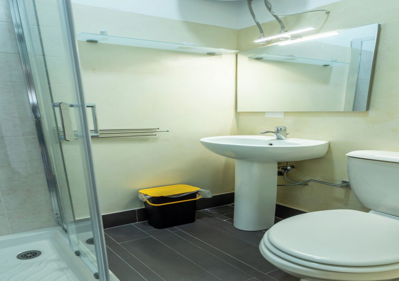 Un baño con cabina de ducha de vidrio, lavamanos e inodoro.