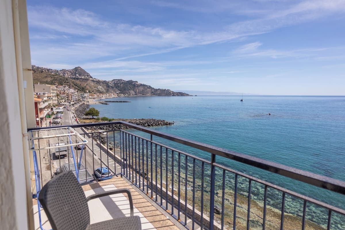 Ein Balkon mit freiem Blick auf eine Küstenstadt, eine felsige Küstenlinie und ein ruhiges Meer.