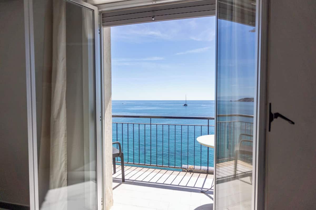 Ein Balkon mit Blick auf das Meer und ein Segelboot.