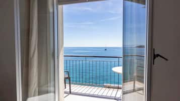 A balcony with a view of the sea and a sailboat.