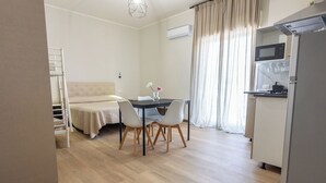 A compact living space with a kitchenette, a dining area, and a bed.