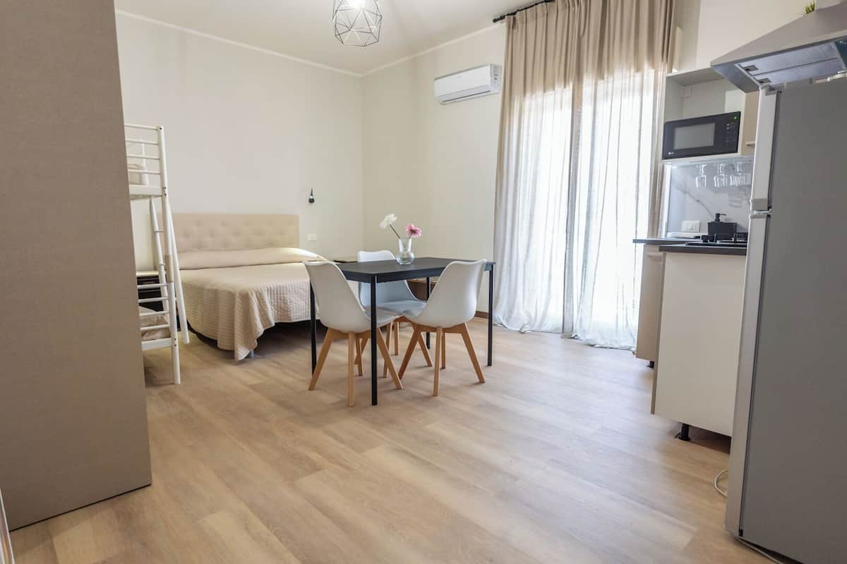 Ein kompakter Wohnraum mit Küchenzeile, Essbereich und Bett.
