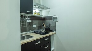 A compact kitchen with a gas stove, a sink, and a microwave. There are cabinets and a small countertop.