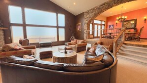 Un salón amplio con un gran ventanal, una chimenea de piedra y una zona de estar acogedora.