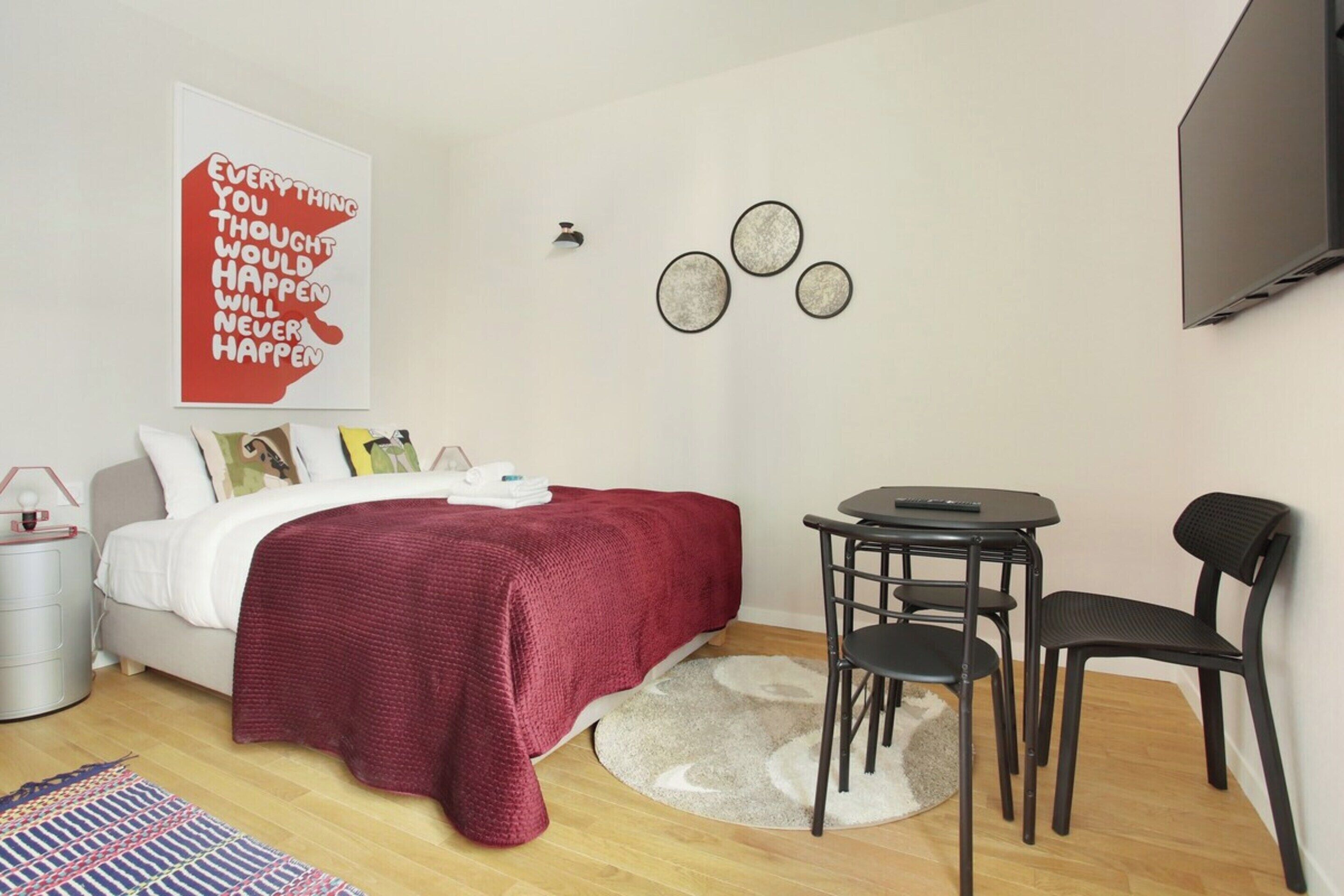 A modern bedroom with a bed, a desk, a chair, and a TV.