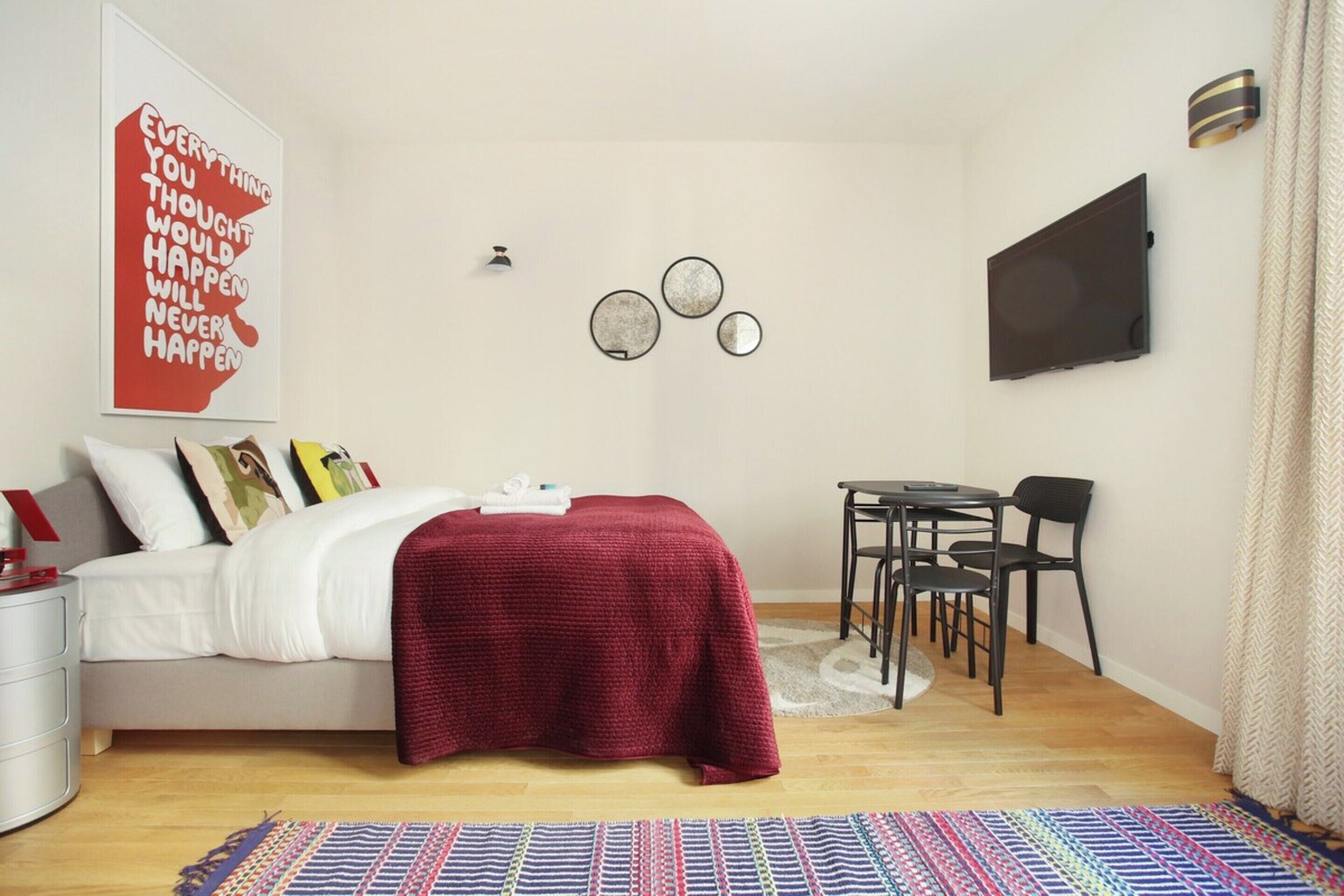 Un dormitorio con cama, escritorio y televisor.
