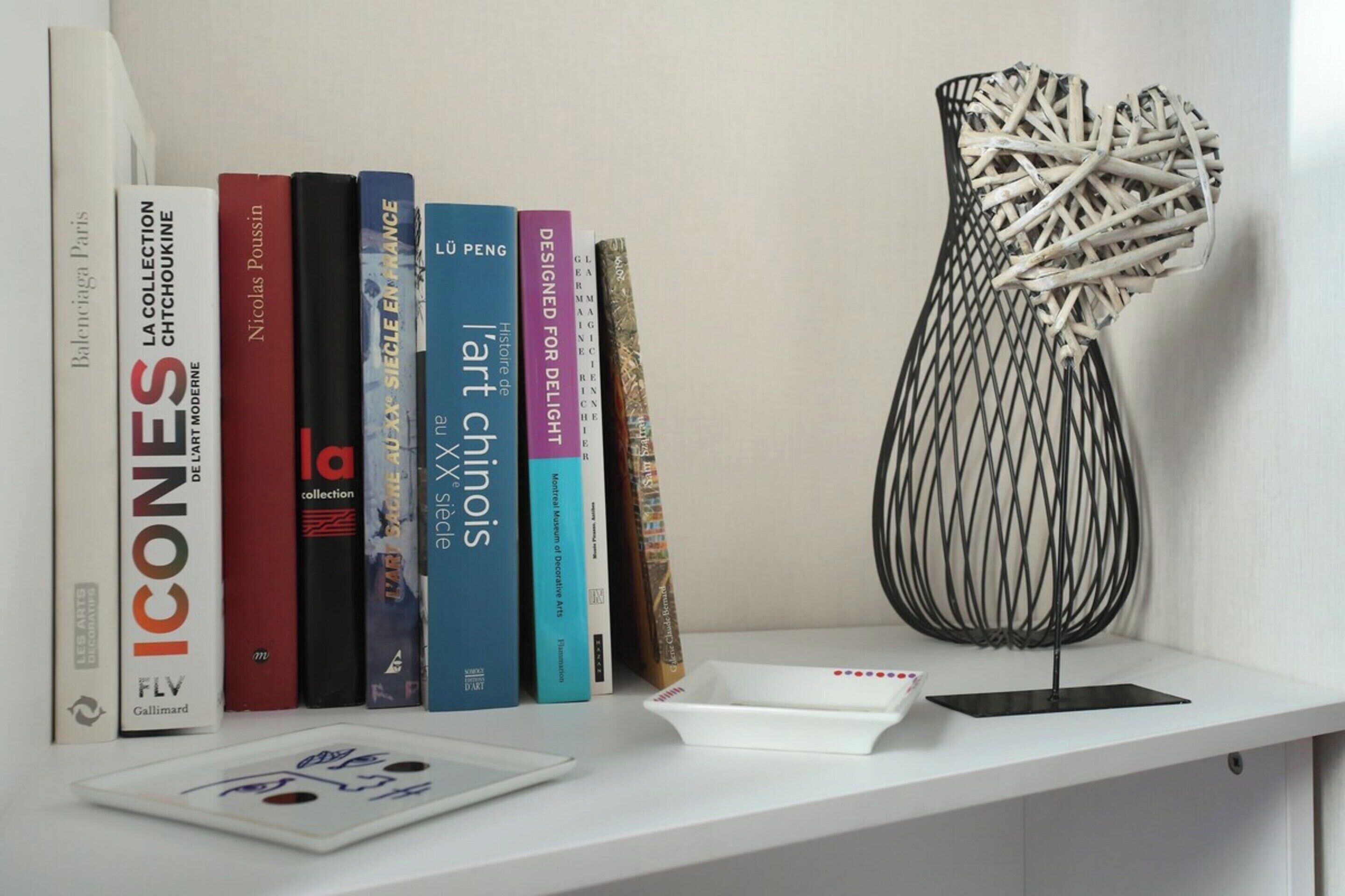 A bookshelf with books and a decorative vase.